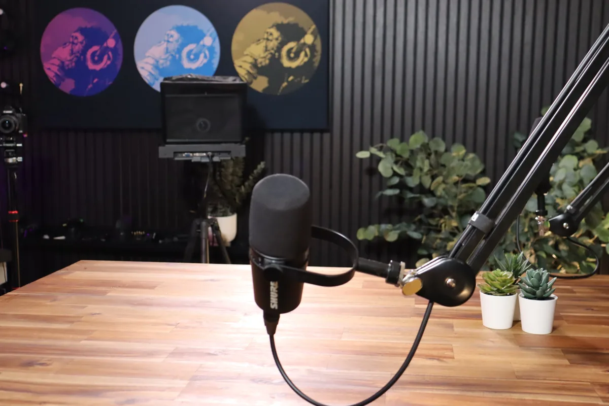 Close-up of a podcast microphone on a boom arm over the studio desk